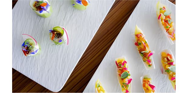 Colourful bite-sized dishes arranged on white serving platters