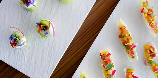 Colourful bite-sized dishes arranged on white serving platters
