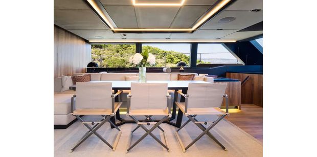 Contemporary dining area with a large table, cushioned seating, and panoramic windows
