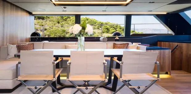 Contemporary dining area with a large table, cushioned seating, and panoramic windows