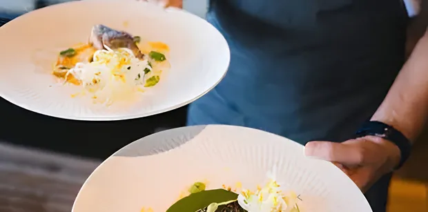Crew member serving two presented plated dishes