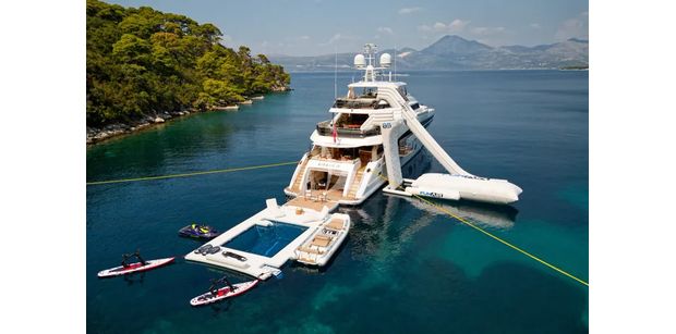 Aerial shot of MIRAGE IV superyacht with water slide, sea pool, and several other water toys set up