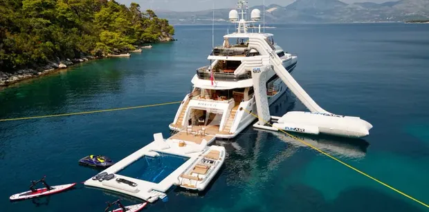 Aerial shot of MIRAGE IV superyacht with water slide, sea pool, and several other water toys set up