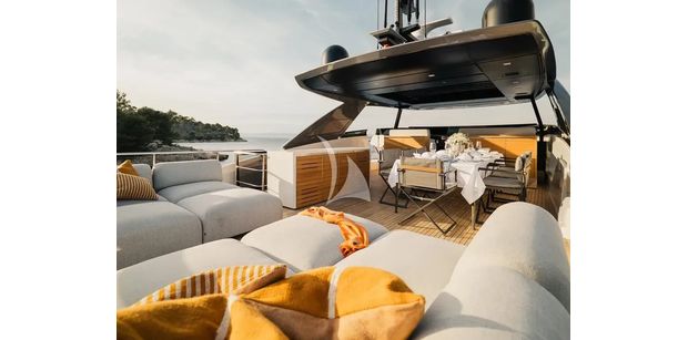 ZATARA II Sanlorenzo SL90A - view of the flybridge deck on ZATARA II, showing plush outdoor sun loungers and a covered dining area set for a meal.