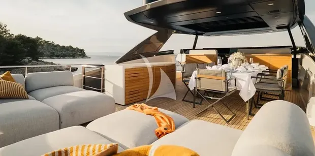 ZATARA II Sanlorenzo SL90A - view of the flybridge deck on ZATARA II, showing plush outdoor sun loungers and a covered dining area set for a meal.