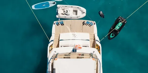 ZATARA II Sanlorenzo SL90A - aerial view of the stern and swim platform of ZATARA II anchored in turquoise waters, surrounded by water toys including paddleboards, a tender, a jet ski, and snorkeling gear.