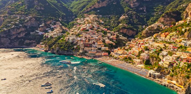 stunning aerial shot of positano with yachts in the coastline