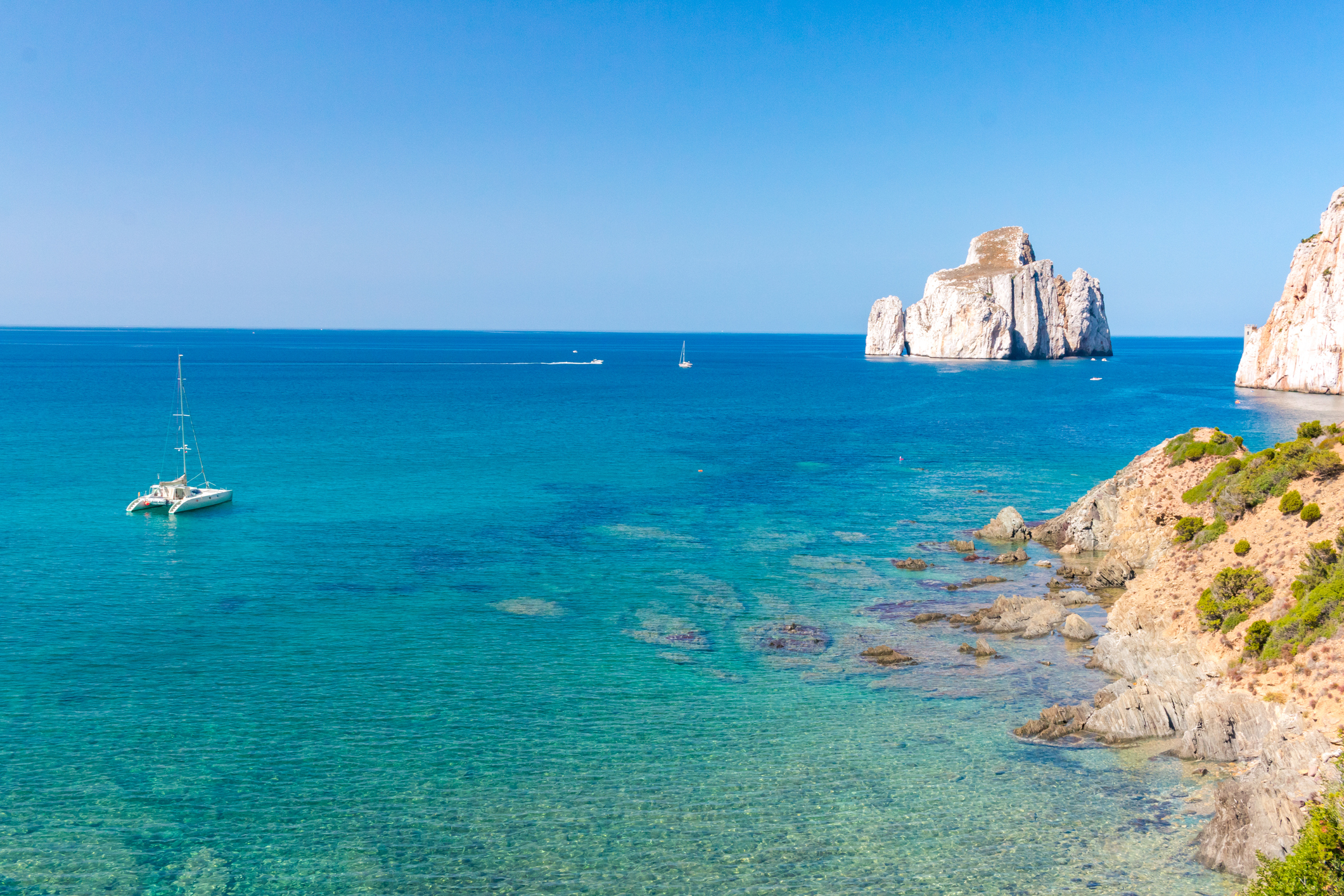 a catamaran anchored in an exclusive anchorage in sardinia highlighting its turquoise water