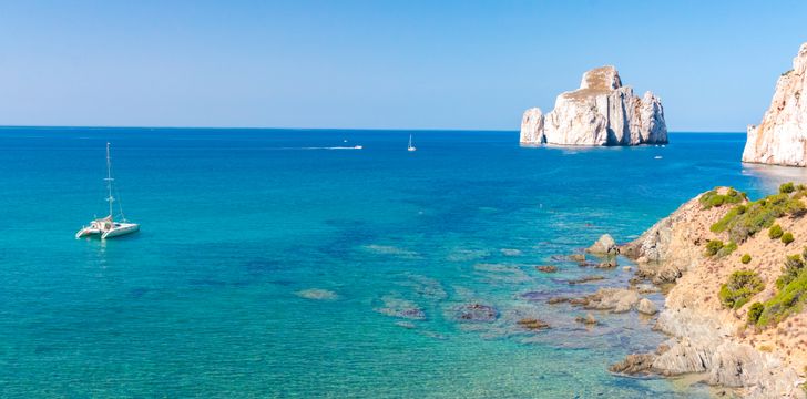 a catamaran anchored in an exclusive anchorage in sardinia highlighting its turquoise water